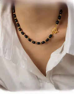 Detail of beaded necklace with black oval agate beads and golden OT toggle clasp on model