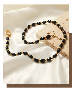 Detail of black oval beads and golden spherical spacers on necklace with OT clasp