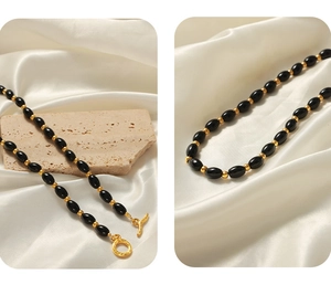 Detail of black oval agate beads and golden OT toggle clasp on a silk background