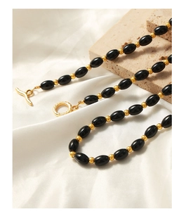 Macro shot of black agate oval beads and golden toggle clasp on a stylish necklace