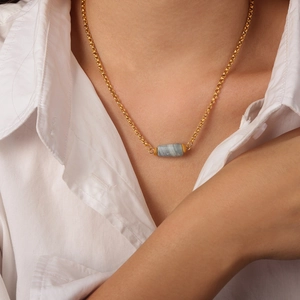 Collana minimalista placcata oro con ciondolo cilindrico in pietra naturale su una modella