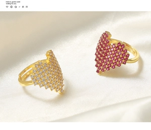 Close-up of gold heart rings with pavé white and pink stones on white silk