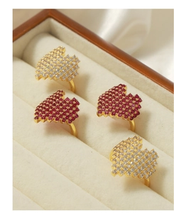 Detailed macro view of four gold-plated fan-shaped rings with red and clear cubic zirconia