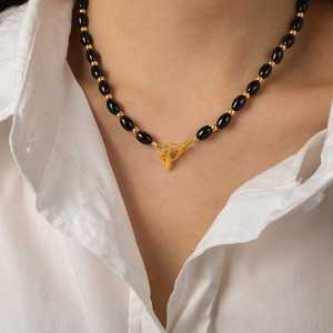Elegant black oval agate beaded necklace with golden toggle clasp on white shirt