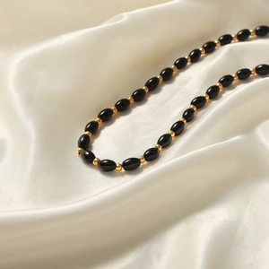 Elegant natural black oval agate beaded necklace with gold spacers on white silk