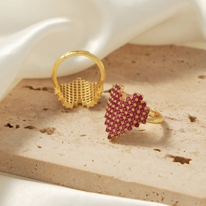 Luxurious gold heart rings set with red cubic zirconia on elegant marble and satin
