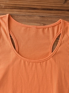 Detail of orange cotton tank top featuring scoop neckline and durable stitching