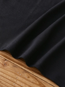 Close-up of black knitted fabric showing premium double-stitched hem and soft texture