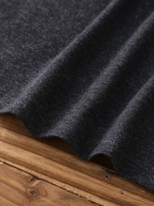 Detail of double-needle hem stitching on dark grey knit fabric against wood background