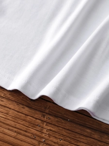Close-up of white cotton ribbed knit fabric with reinforced double-needle stitching hem