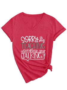 Detail of red V-neck T-shirt with 'Sorry Is My Teaching' slogan and stylish knotted hem