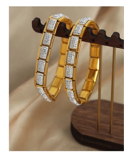 Macro shot of gold square link bracelets with sparkling crystal pavé on a jewelry stand