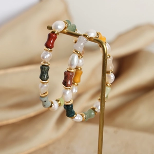 Boucles d'oreilles créoles avec perles d'eau douce et pierres colorées sur soie beige