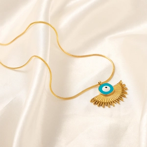 Gold evil eye pendant necklace with fan shape on silk background in a bohemian style