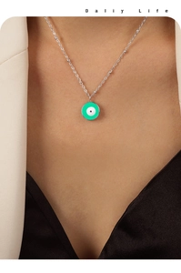 Détail du collier avec pendentif œil maléfique en émail vert sur chaîne perlée