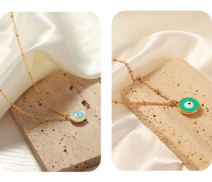 Détail de pendentifs œil maléfique en émail bleu clair et vert sur chaînes dorées