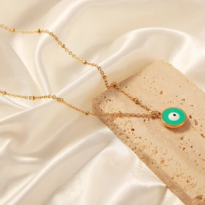 Collier en plaqué or avec pendentif œil maléfique en émail vert sur fond de soie