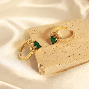Anelli a corona dorati con zircone verde a cuore su elegante sfondo di seta bianca