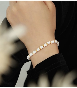 Detail of beaded shell heishi bracelet with gold accents on a model wrist