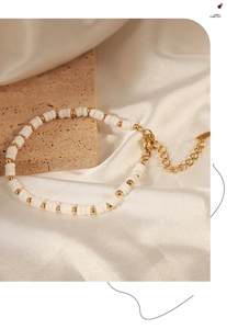 Close-up of white shell beads and gold titanium steel spacers on a handcrafted bracelet