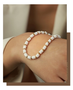 Detailed shot of handmade beaded bracelet with white shell discs and gold steel beads