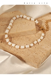 Close-up of white shell beads and golden steel beads with adjustable lobster clasp