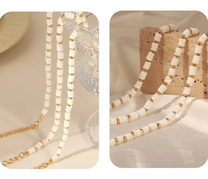 Detail of bohemian shell beads and gold titanium steel beads on a white bracelet cord