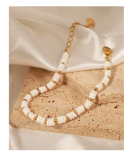 Detail of white shell beads and golden steel beads with lobster clasp and extension chain