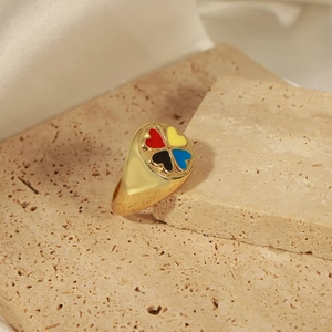 Gros plan d'une bague chevalière dorée avec trèfle à quatre feuilles en émail coloré