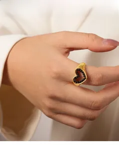 Dettaglio di un elegante anello a cuore dorato con perle nere indossato per uno stile unico