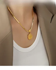 Close-up of 18k gold plated portrait coin pendant on a sleek snake chain necklace