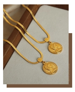 Macro shot of 18k gold-plated snake chains with Elizabeth II coin pendants on wood base