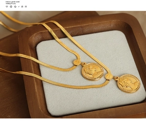 Macro view of double 18k gold plated snake chains with vintage portrait coin pendants