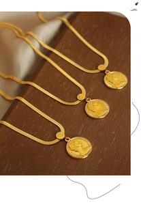 Macro detail of triple gold snake chain necklaces with 1981 Elizabeth II coin pendants