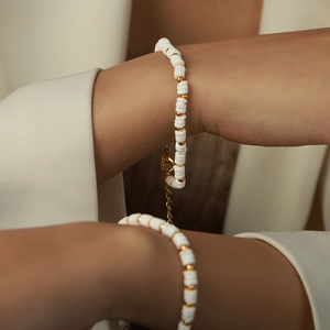 Handmade white shell disc and gold bead bracelet with lobster clasp on female wrist