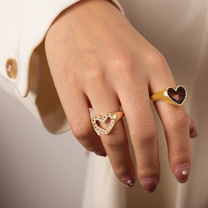 Eleganti anelli a cuore dorati minimalisti con perle e perline nere sulla mano