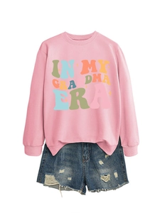 Detailansicht eines rosa Sweatshirts mit In My Grandma Era Text und Denim-Shorts
