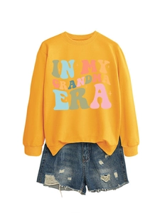 Detail von gelbem Sweatshirt mit IN MY GRANDMA ERA Druck und ausgefransten Jeans
