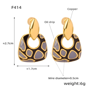 Detalle de pendientes geométricos de cobre chapados en oro 18k con esmalte gris y negro