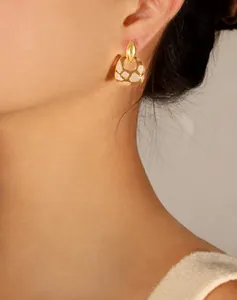 Primer plano de pendientes geométricos chapados en oro con esmalte en una modelo