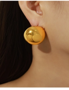 Macro close-up of large polished gold dome earrings featuring high-shine mirror finish