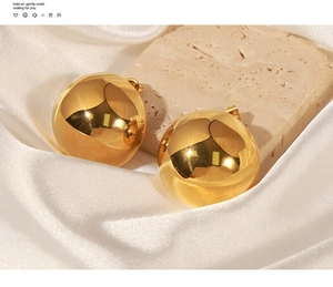 Detailed view of polished golden dome earrings on luxury white satin and stone