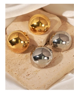 Close-up of gold and silver hollow round earrings on travertine stone with satin silk