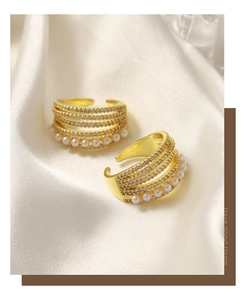 Macro detail of multi-layer gold ring with zircons and pearls on white silk