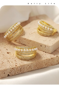 Close-up of golden multi-layer rings with white pearls and pave cubic zirconia