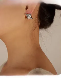 Detail of silver irregular wavy earring with bead texture on model side view