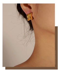 Close-up of gold geometric quadrilateral earrings worn by a model for a vintage look