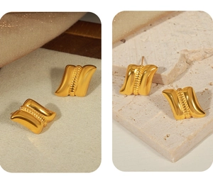 Detail of gold-plated square earrings with vertical bead texture on stone surface