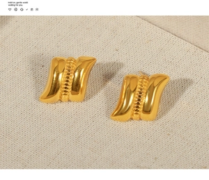 Close-up of gold-plated geometric earrings with wavy rectangle texture and bead detail