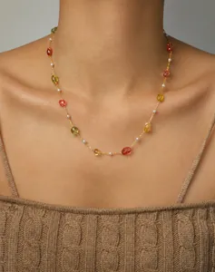 Détail d'un collier doré avec pierres précieuses colorées et perles sur un mannequin